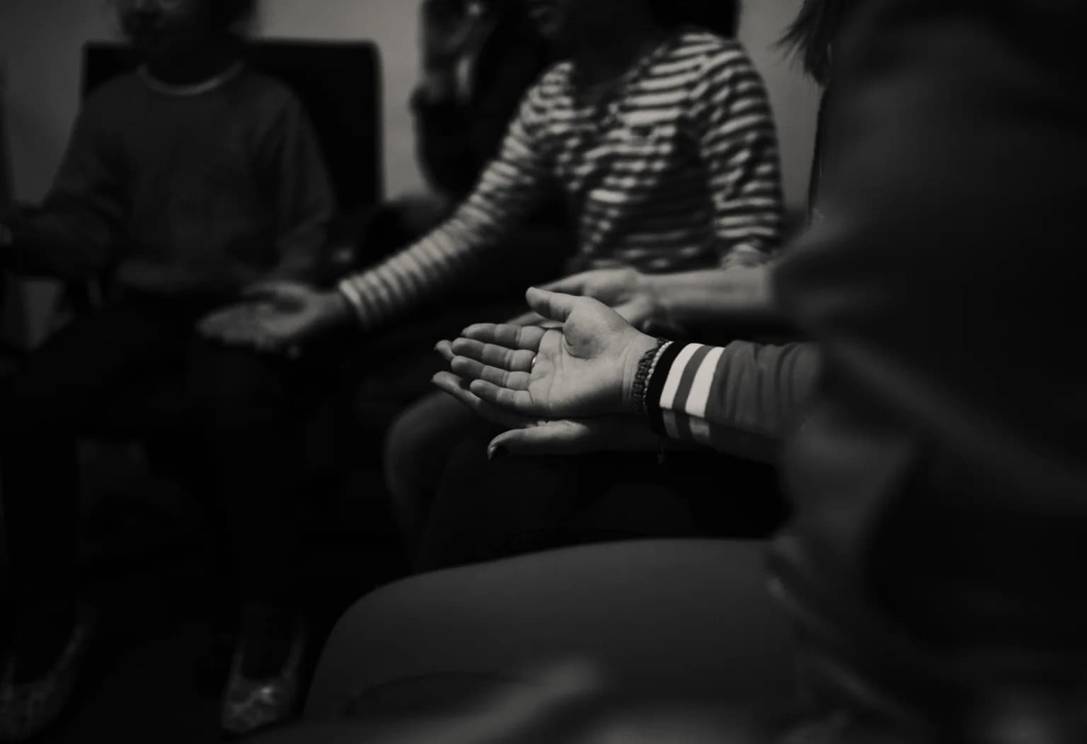 Mâinile unor participanți așezați împreună, într-o fotografie alb-negru