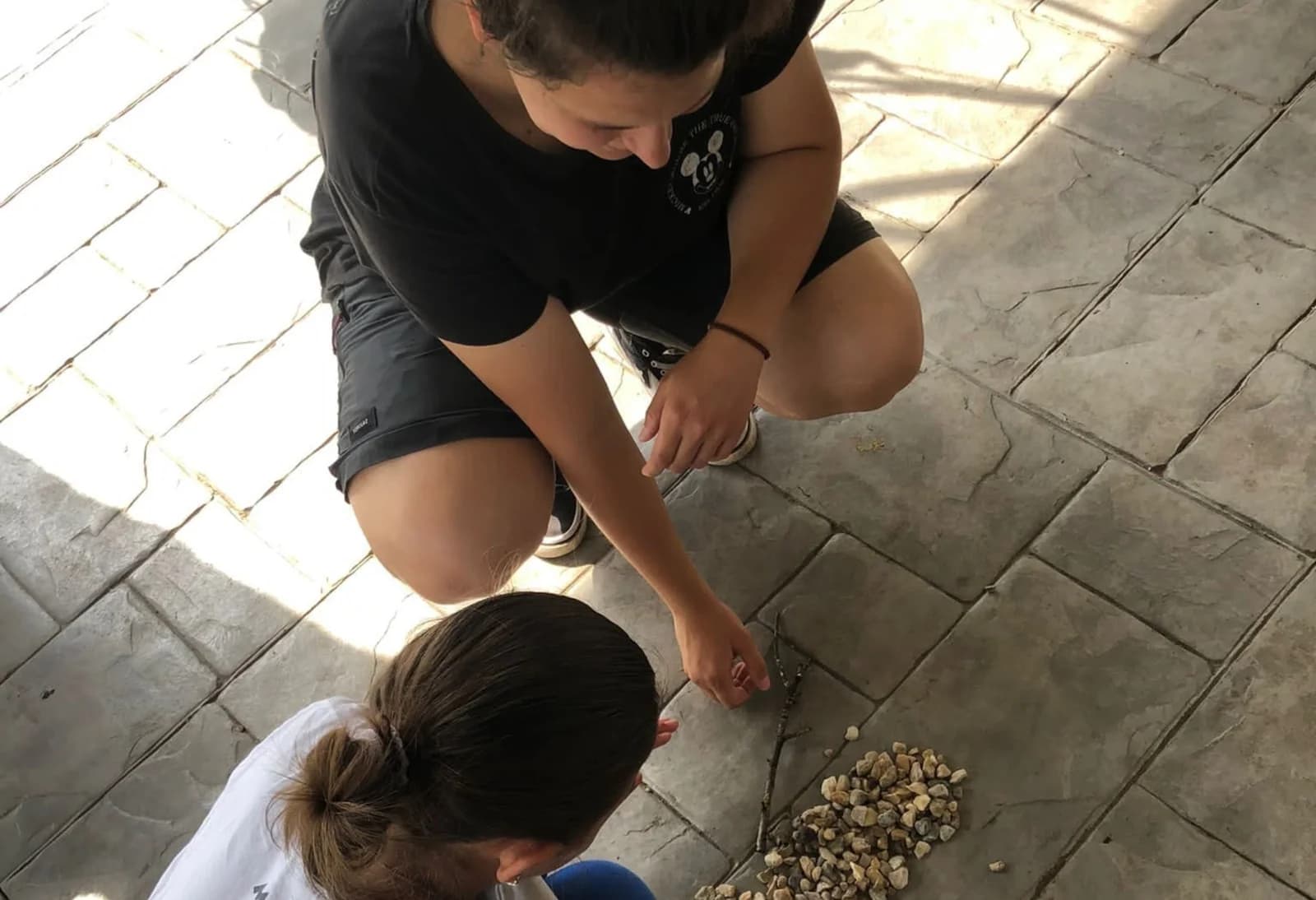 O voluntară și un copil creează împreună cu materiale naturale